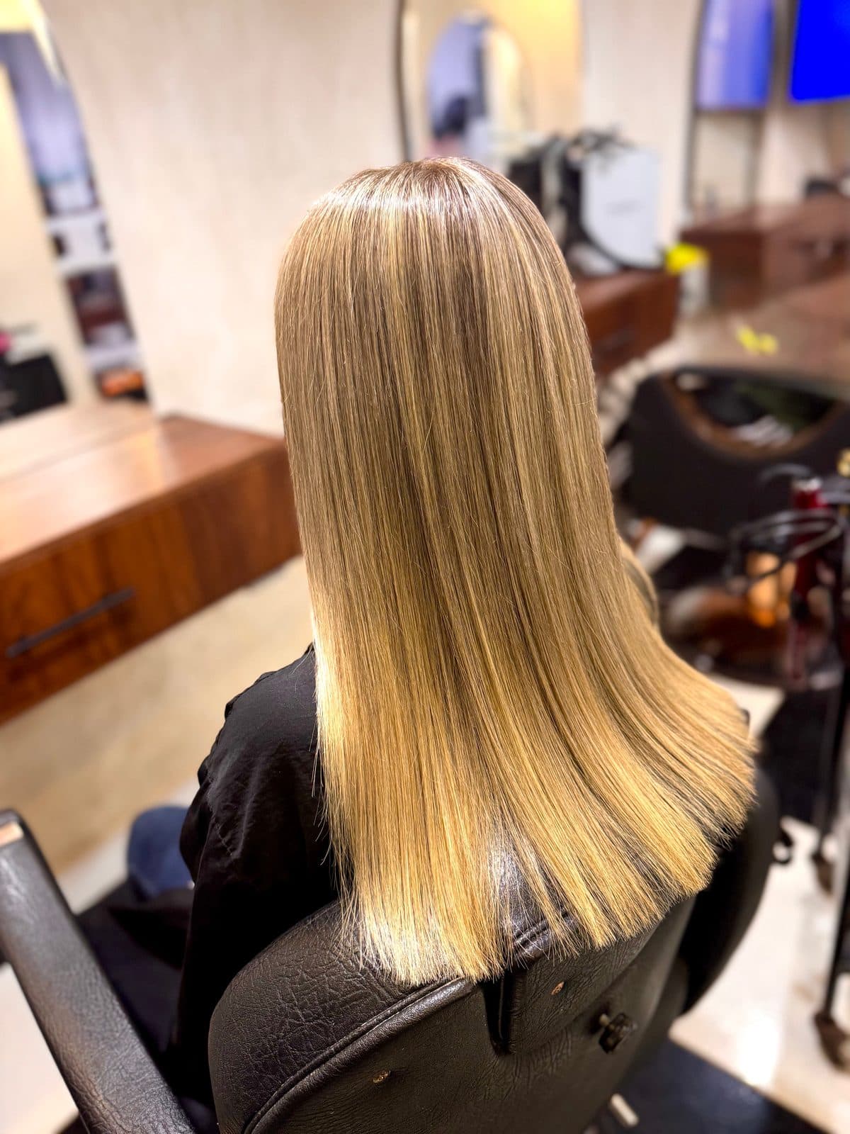 Cabello rubio, liso y brillante, visto de espaldas en el salón.